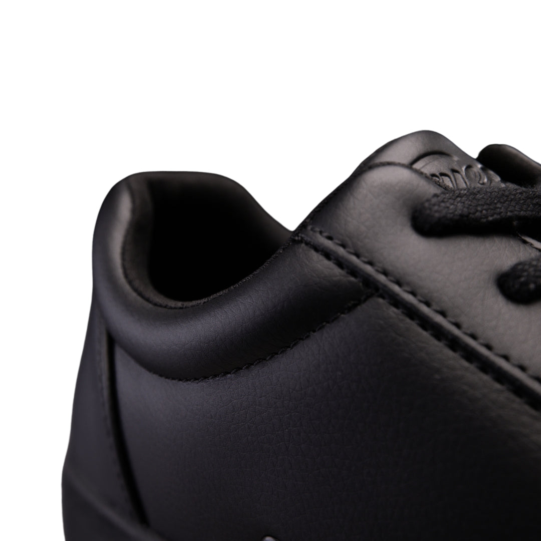 Nahaufnahme der Fuego Low-Top-Tanz-Sneakers in Schwarz, die ihre glatte Lederstruktur und die schwarzen Schnürsenkel hervorheben.